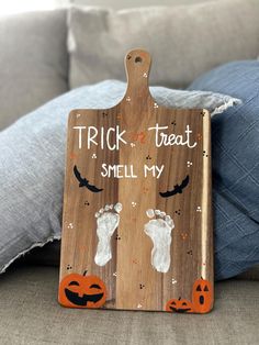 a wooden sign that says trick treat smell my hand and foot prints on the front