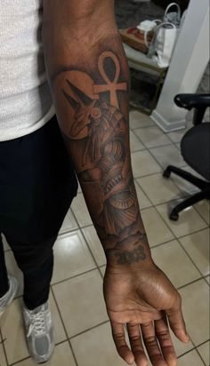 a man with a tattoo on his arm and hand holding scissors in the other hand