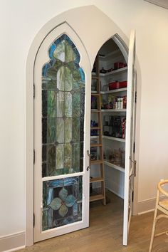 an open door with stained glass in the center and shelves on either side, next to a ladder