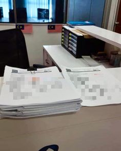 an office cubicle with stacks of papers on the desk