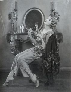 an old fashion photo of a woman sitting in front of a mirror