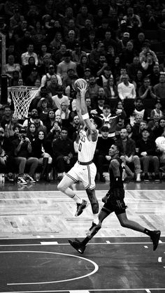 black and white photograph of basketball players in action on court with crowd watching from bleachers