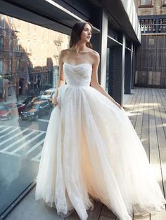 a woman in a wedding dress standing on the sidewalk