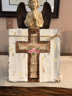 an old wooden cross with angel wings on it and a pink flower in the center