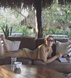 a woman laying on top of a couch next to a table