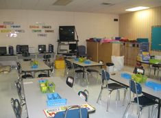 an empty classroom with desks and chairs in front of a television set on the wall