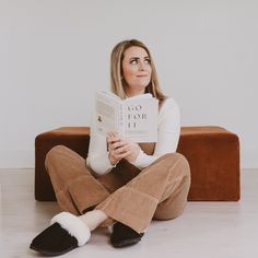 a woman sitting on the floor reading a book