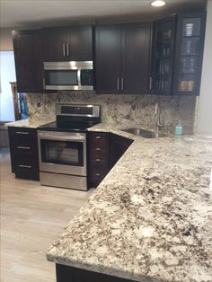 a kitchen with granite counter tops and stainless steel appliances in the center, along with dark wood cabinets