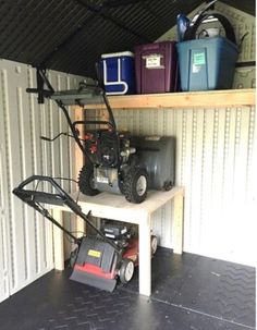 a garage with shelves and tools on the floor, including a lawn mower sitting on top of a work bench