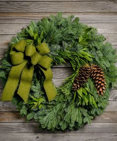 a green wreath with pine cones and evergreen leaves on a wooden background, ready to be decorated for christmas