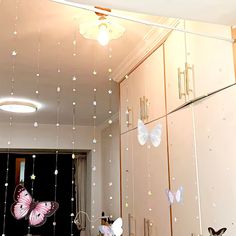 some butterflies are hanging from the ceiling in a room with pink walls and white cupboards