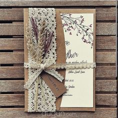 the wedding card is wrapped in lace and tied with twine on wooden planks