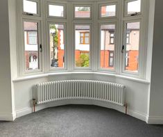 an empty corner room with three windows and a radiator