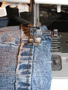 the sewing machine is working on some blue jeans