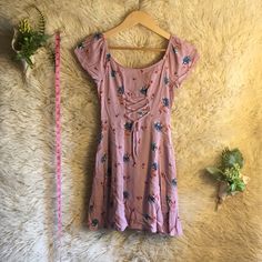 a pink top sitting on top of a white rug next to a plant and measuring tape