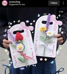 two handmade tags with flowers on them are being held by someone's hands