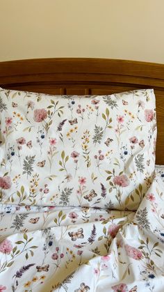 an unmade bed with floral sheets and pillowcases on top of the headboard