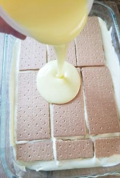 someone is pouring cream on top of crackers in a glass dish with white icing