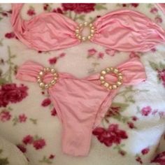 two pink bikinisuits with pearls and flowers on the bottom are laying on a bed