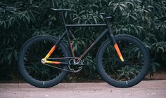 a black and orange bike parked in front of some bushes