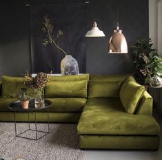 a living room with green couches and plants on the table in front of it