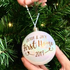 someone holding up a personalized ornament on a christmas tree