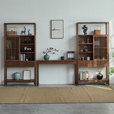 two wooden shelves with books and vases on them in front of a white wall