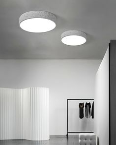 a white room with two round lights and clothes hanging on the wall in front of it