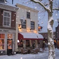 the outside of a restaurant in winter with snow on the ground and tables covered by umbrellas