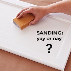 a person's hand holding a sanding block on top of a white board