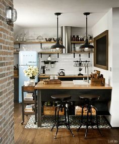 a kitchen with two stools and an island in the middle, surrounded by brick walls