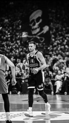 black and white photograph of basketball players on court with fans in the bleachers