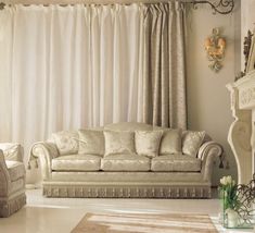 a living room with white furniture and curtains