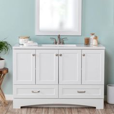 a white bathroom vanity with two sinks and mirror above it, in front of a blue wall