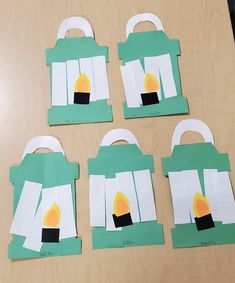 four pieces of paper cut out to look like bags with candles on them sitting on a table