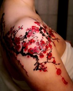 a woman's arm with red flowers and branches painted on the back of it