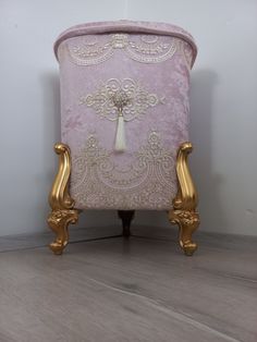 a pink and gold chair sitting on top of a wooden floor next to a white wall