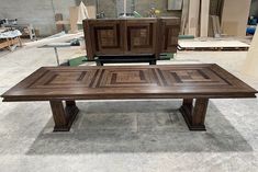 a large wooden table sitting on top of a cement floor next to a pile of boxes