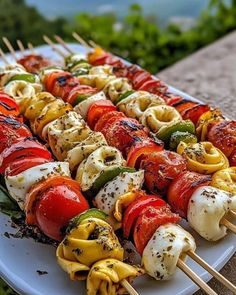 several skewers filled with different types of vegetables and sauces on a white platter