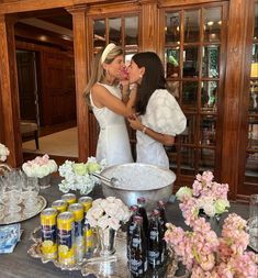 two women kissing in front of a table full of drinks