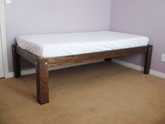 a wooden bed frame sitting on top of carpeted floor next to a purple wall