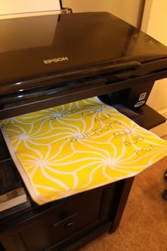 a printer sitting on top of a desk next to a yellow and white paper towel