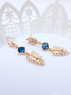 Enhance your look with these stunning Art Deco Leaf Navy Earrings. The navy blue sapphire color adds a touch of elegance to any outfit, making them an excellent accessory for any occasion. Eye-catching Design: The Art Deco design of these earrings is sure to make you stand out from the crowd. Boho Bridal Accessory: Perfect for boho brides, bridesmaids, maid of honor and as a gift for her on her special day. Premium Quality: These earrings are made with high-quality materials that are sure to las Blue Dangle Bridal Earrings For Celebration, Blue Drop Earrings For Bridal Celebration, Elegant Blue Earrings For Party, Elegant Blue Chandelier Earrings For Celebration, Elegant Dangle Crystal Earrings For Gift, Blue Drop Bridal Earrings For Celebration, Blue Dangle Bridal Earrings Gift, Elegant Blue Bridal Earrings For Celebration, Blue Drop Earrings For Bridal Gift