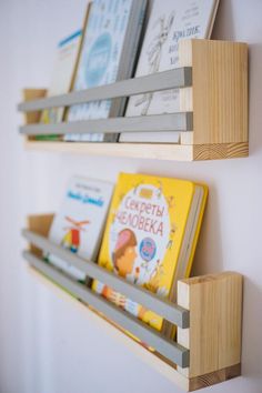 two wooden bookshelves holding children's books on the side of a wall