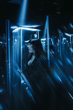 a woman is standing in the middle of a room with blue light coming from behind her