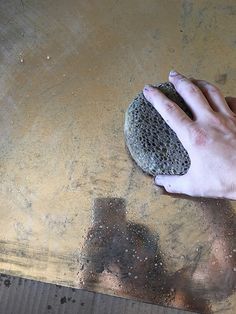 a person's hand holding a rock on top of a table