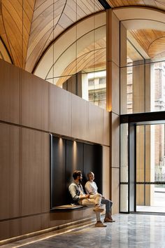 two people sitting on a bench in a building