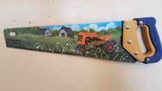 a pair of scissors hanging on a wall with a farm scene painted on the blades