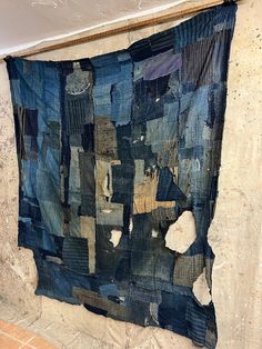 a blue piece of cloth hanging on the wall next to a tile floor with holes in it