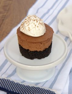 a piece of chocolate cake with whipped cream on top sitting on a white plate next to a blue and white napkin